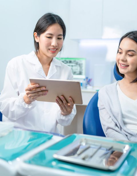 asian dentist holding digital tablet and giving ad 2023 11 27 05 28 36 utc 1 scaled